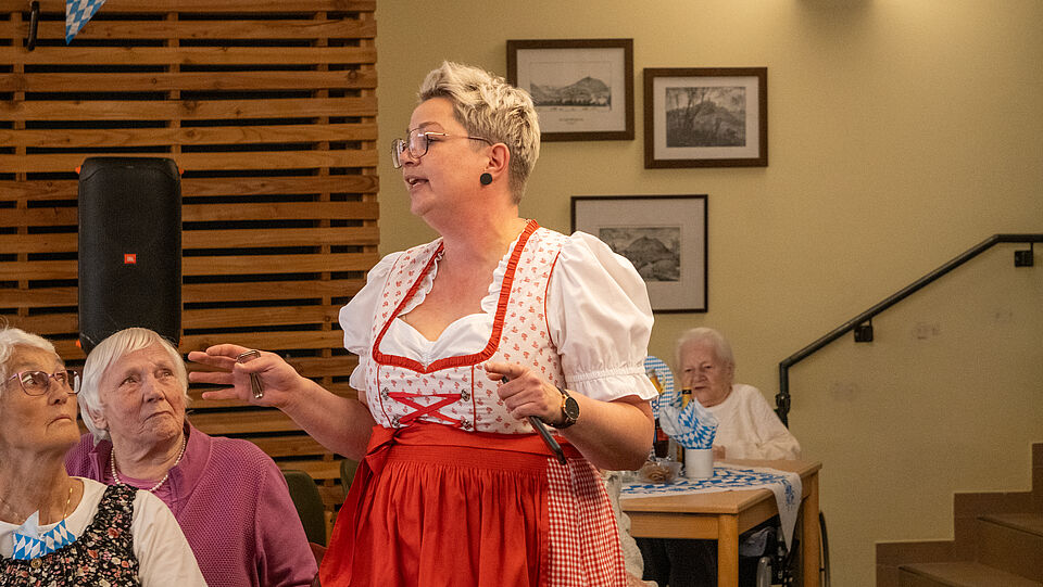 8465 Eine Frau vom sozialen Dienst hält in einem Dirndl eine Festansprache vor den Seniorinnen und Senioren