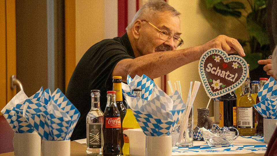 8404 Gedeckter Tisch in bayrischer Beflaggung. Ein Herz steht auf dem Tisch mit dem Text "Schatzl" Ein Mann reicht einer anderen Person etwas